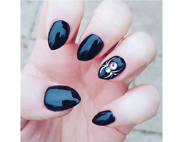 Smalto nero lucido con accent nail di cristalli, con ragno stilizzato. Photo credit: Instagram @captainchar